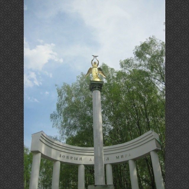 sky, tree, text, communication, low angle view, western script, cloud - sky, railing, day, animal representation, built structure, cloud, no people, outdoors, human representation, pole, street light, sign, architecture, non-western script