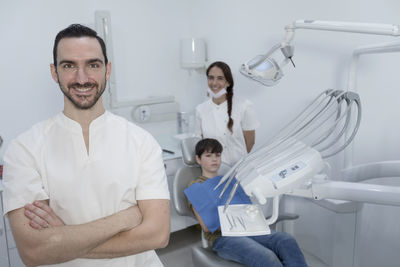 Portrait of confident dentist with boy lying on chair