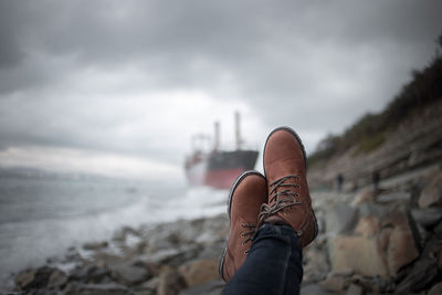 Low section of man wearing shoes on beach