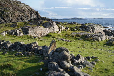 Scenic view of rocks on shore against sky