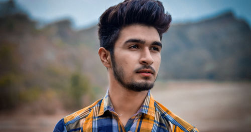 Close-up of thoughtful young man standing on field