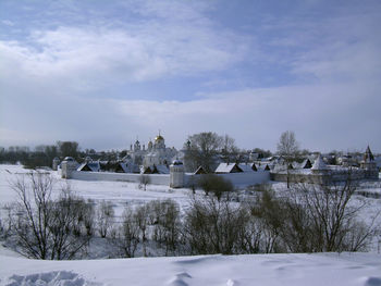 Buildings on snow covered land against sky