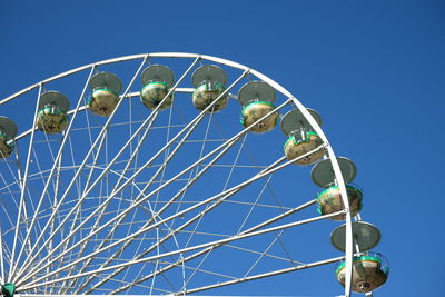 Low angle view of ferris wheel against clear blue sky