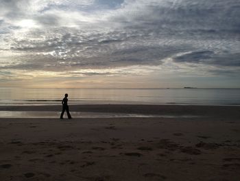 Full length of man on beach against sky during sunset