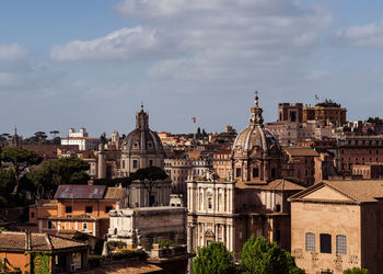 Buildings in city against cloudy sky