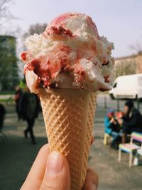 Hand holding cherry yogurt ice cream cone
