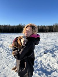 Portrait of young woman with dog on snow covered field