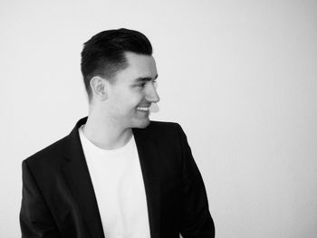 Smiling young man looking away against white background