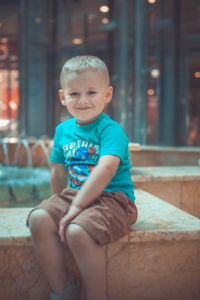 Portrait of smiling boy sitting by fountain