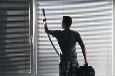 Rear view of man standing against window