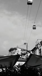 Low angle view of overhead cable cars against sky