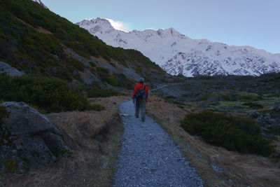 Rear view of man walking on mountain against sky