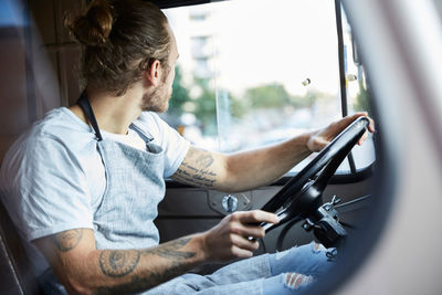 Young man looking out the window while driving food truck in city