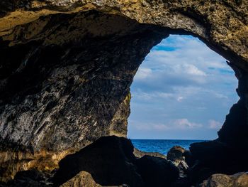 Rock formation by sea against sky