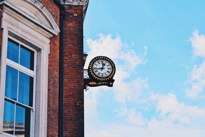 Low angle view of clock against sky