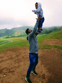 Man playing with baby boy on landscape