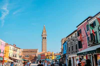 Group of people in front of buildings against blue sky