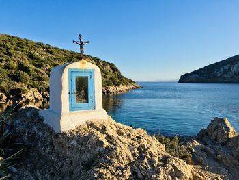 Cross on rock against blue sky