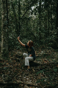 Full length of young man using mobile phone in forest