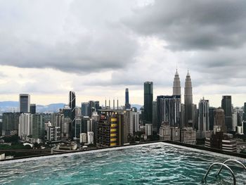 Modern buildings by swimming pool against sky