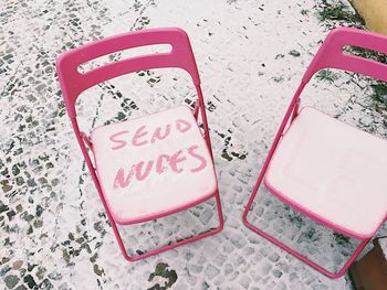 High angle view of text on snow covered chairs at footpath