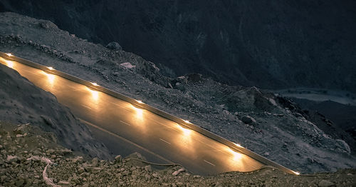 Road by illuminated mountains at night