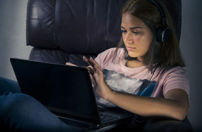 Cute girl using laptop sitting on sofa at home