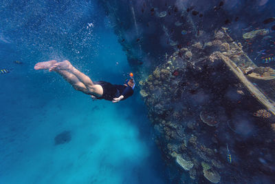 Man swimming on vacation by shipwreck in sea