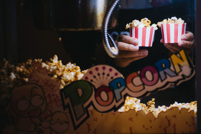 Hands holding popcorns in containers