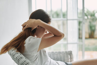 Midsection of woman sitting by window at home