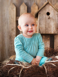 Portrait of cute baby girl sitting on wood