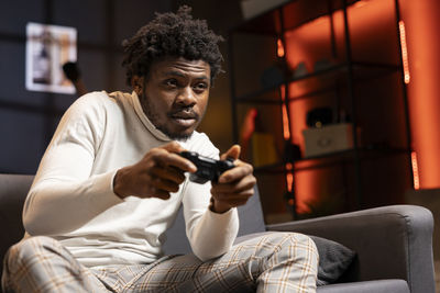 Young man using mobile phone while sitting on sofa at home