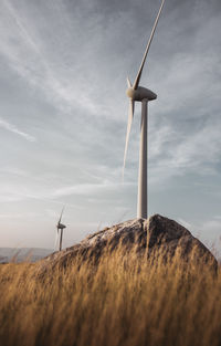 Wind turbines on field against sky