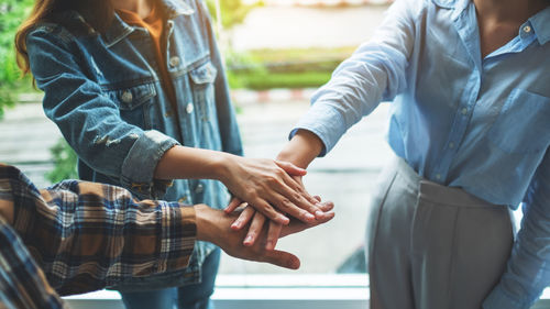 Midsection of business colleagues stacking hands