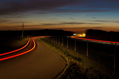 Light trails on road against sky at night