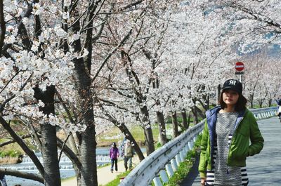 Woman looking away while standing by flowers on trees