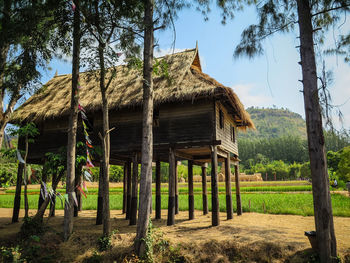 Built structure by trees on field against sky