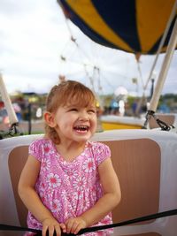 Happy boy sitting on boat sailing against sky