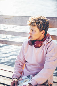 Young man sitting on bench during sunny day