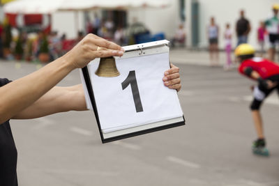 Cropped hand holding bell and folder with number 1