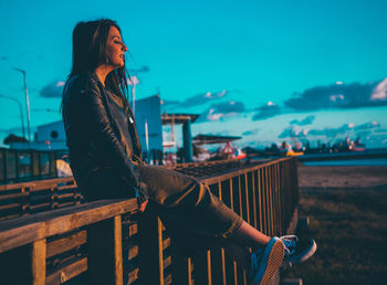 Young woman standing by railing against sea