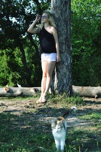 Full length of young woman standing on tree trunk in forest