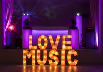 Illuminated love music text in darkroom