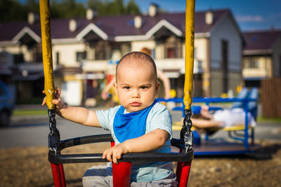 Cute baby boy swinging at playground outdoors