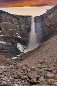 Powerful cascades of hengifoss waterfall falling from mountains against sky
