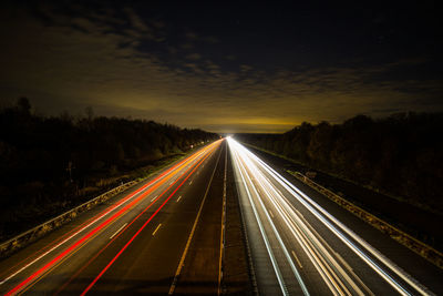 Light trails on road against sky at night