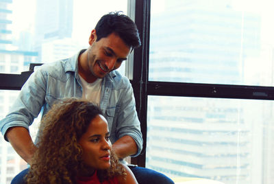 Portrait of young man with daughter against window