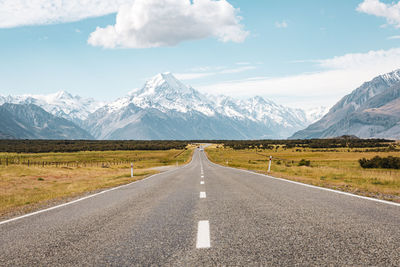 Road leading towards mountains against sky