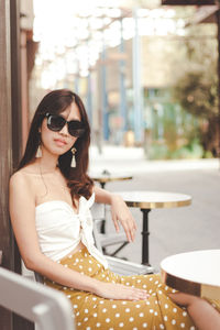 Portrait of young woman sitting on sidewalk cafe 