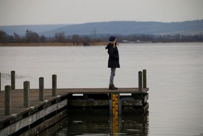 Woman standing on pier over lake